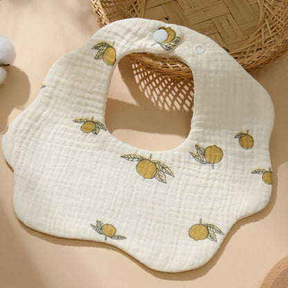 WhisperSoft™ cotton bib in cream with yellow fruit and leaf patterns, featuring a snap closure.