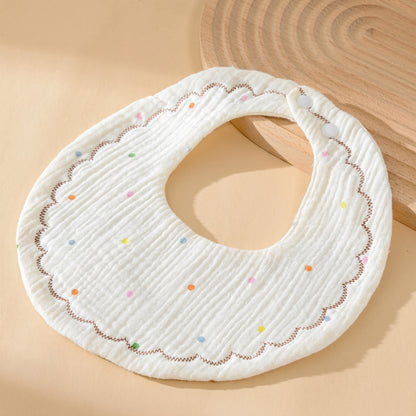 WhisperSoft™ cotton bib in white with colorful dots and scalloped edges, displayed on a light background.