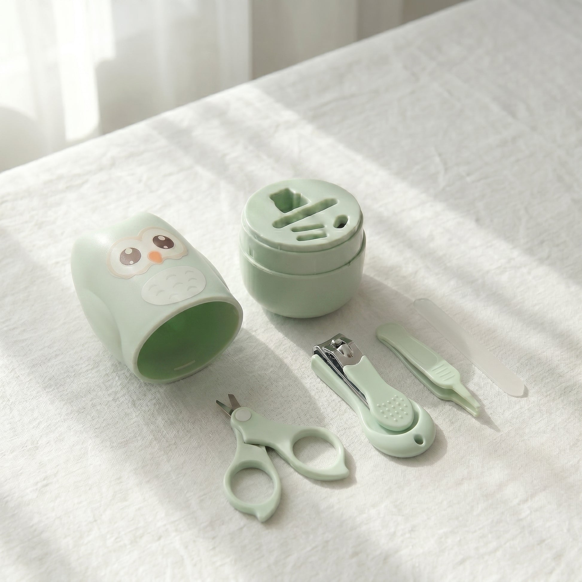 WhisperCare™ baby care kit in green, featuring an owl-shaped case, baby nail clippers, safety scissors, and a nail file.